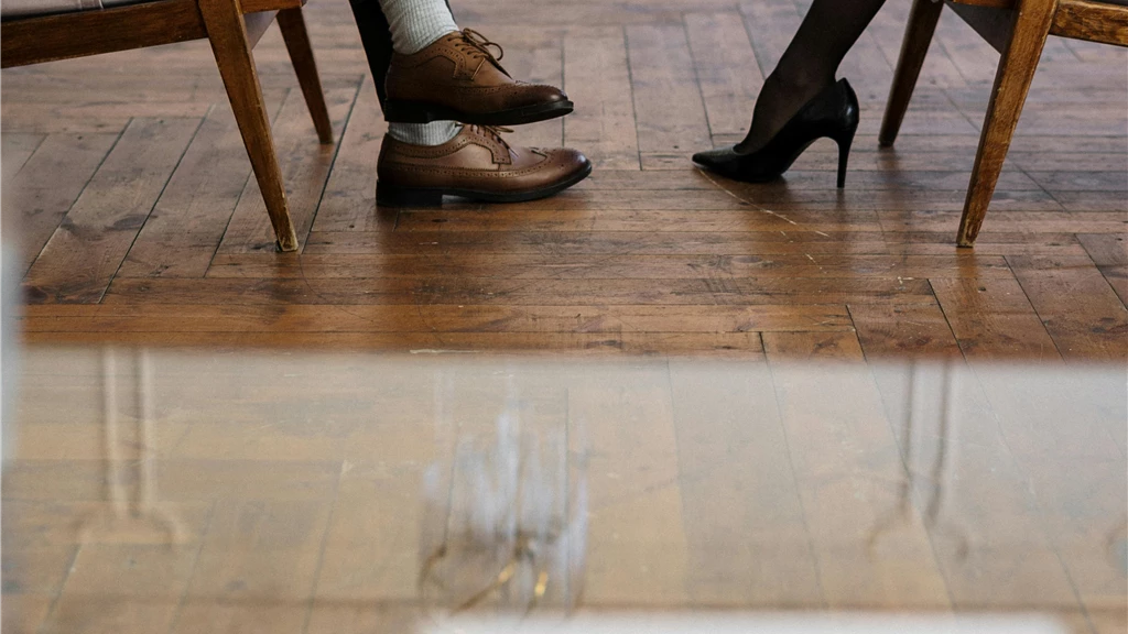 A photo capturing a professional counseling session with two individuals sitting on chairs, focusing on legs and shoes.