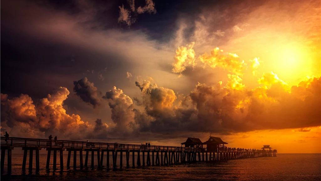 A breathtaking sunset over a scenic ocean pier, capturing vibrant clouds and silhouettes.