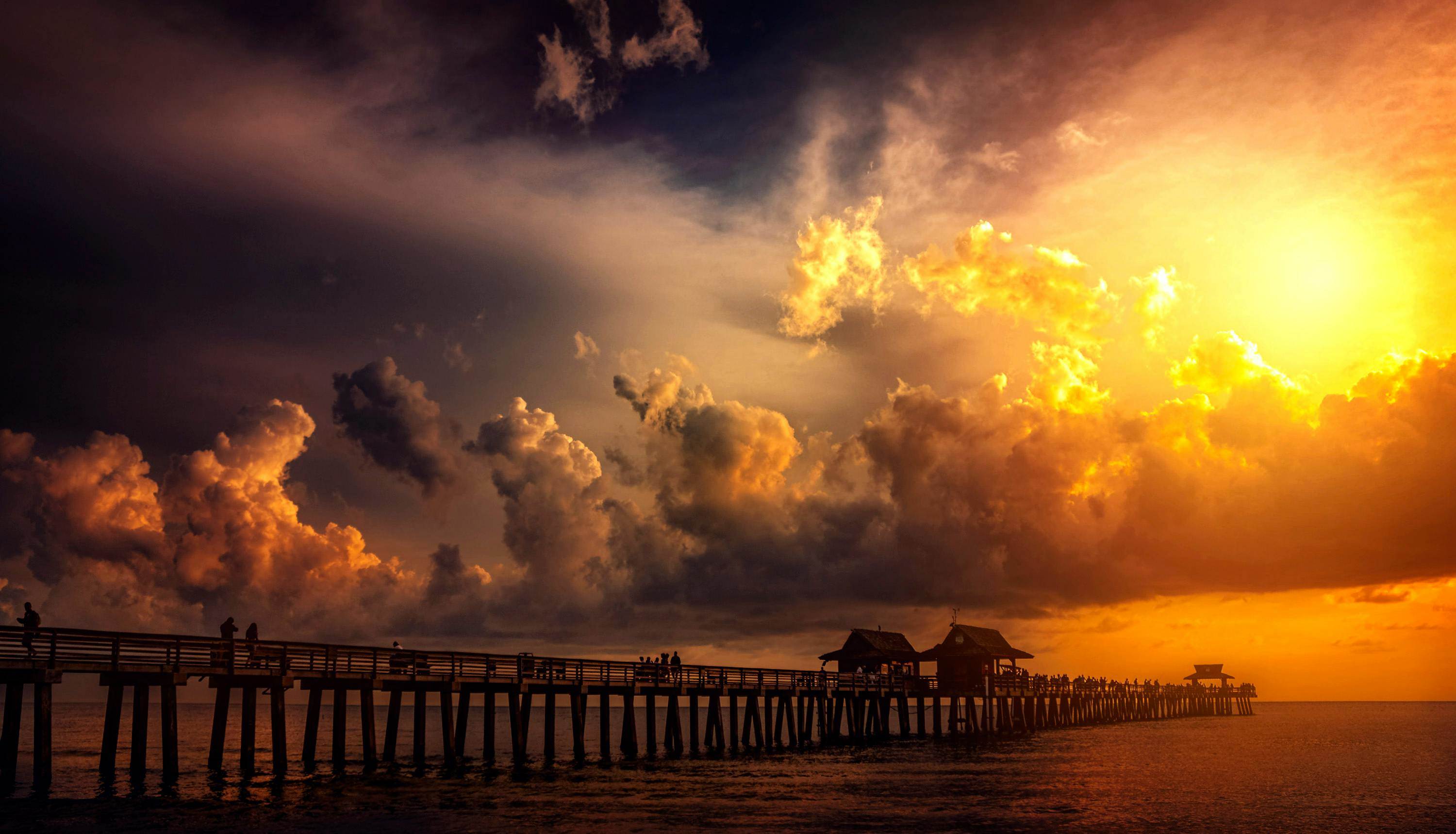 A breathtaking sunset over a scenic ocean pier, capturing vibrant clouds and silhouettes.