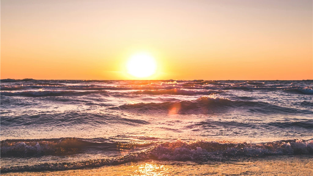 Experience the serene sunset over Ludington Beach with vibrant colors and tranquil waves.