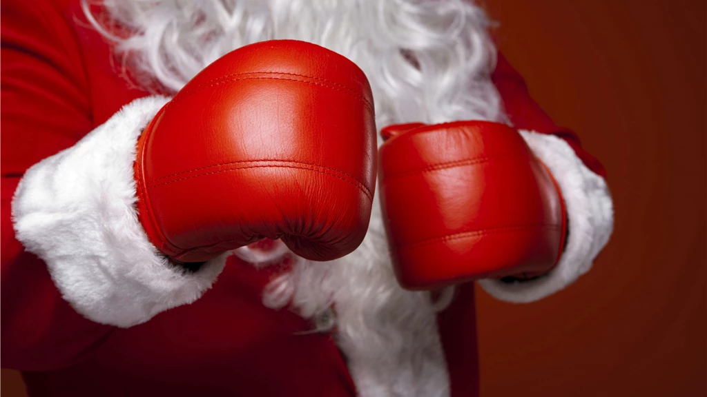 Santa Claus wearing red boxing gloves, ready for the holiday season. Close-up of costume and gloves.
