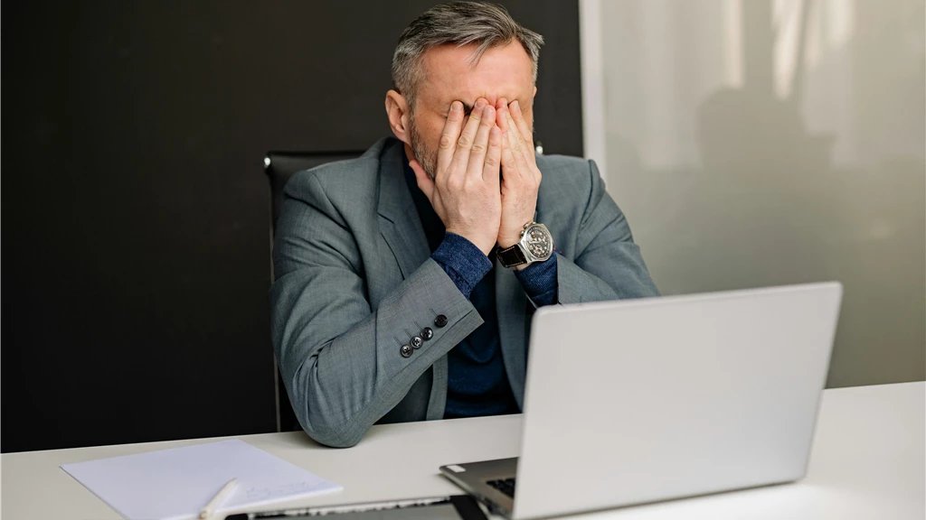 Businessman in gray suit showing frustration while working in office.