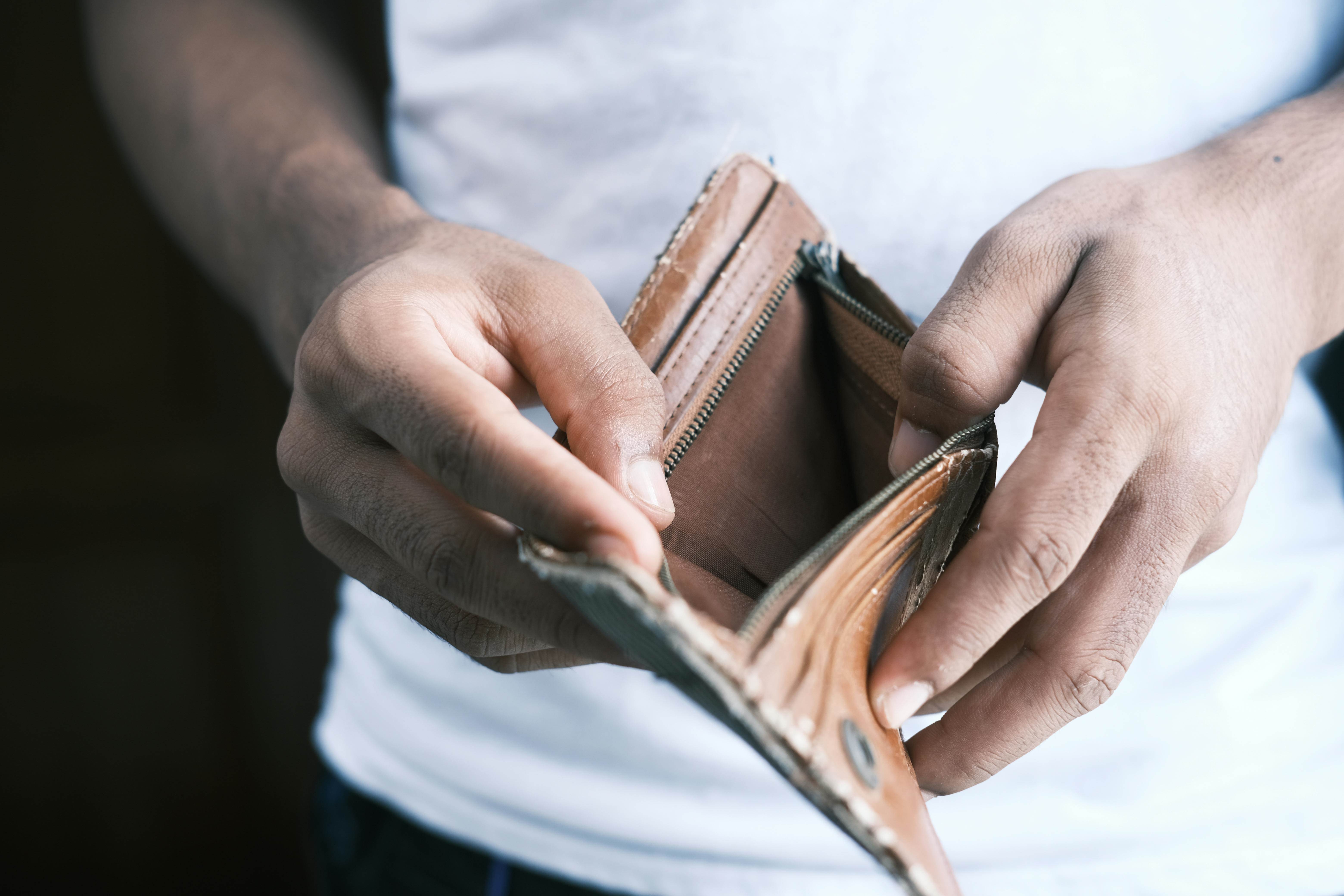 Close-up of hands holding an empty wallet, highlighting financial struggles and economic crisis.