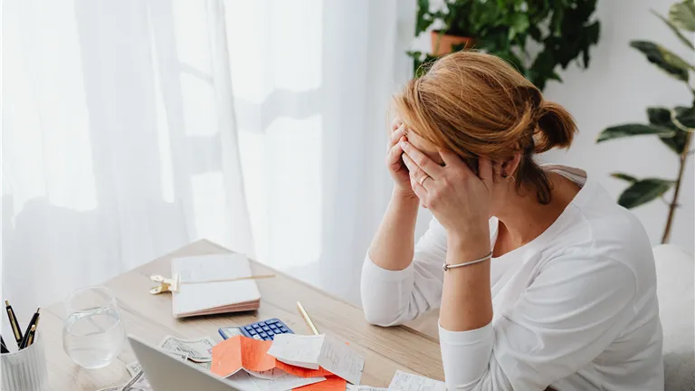 Woman stressed over financial receipts at a desk, dealing with expenses and calculations.